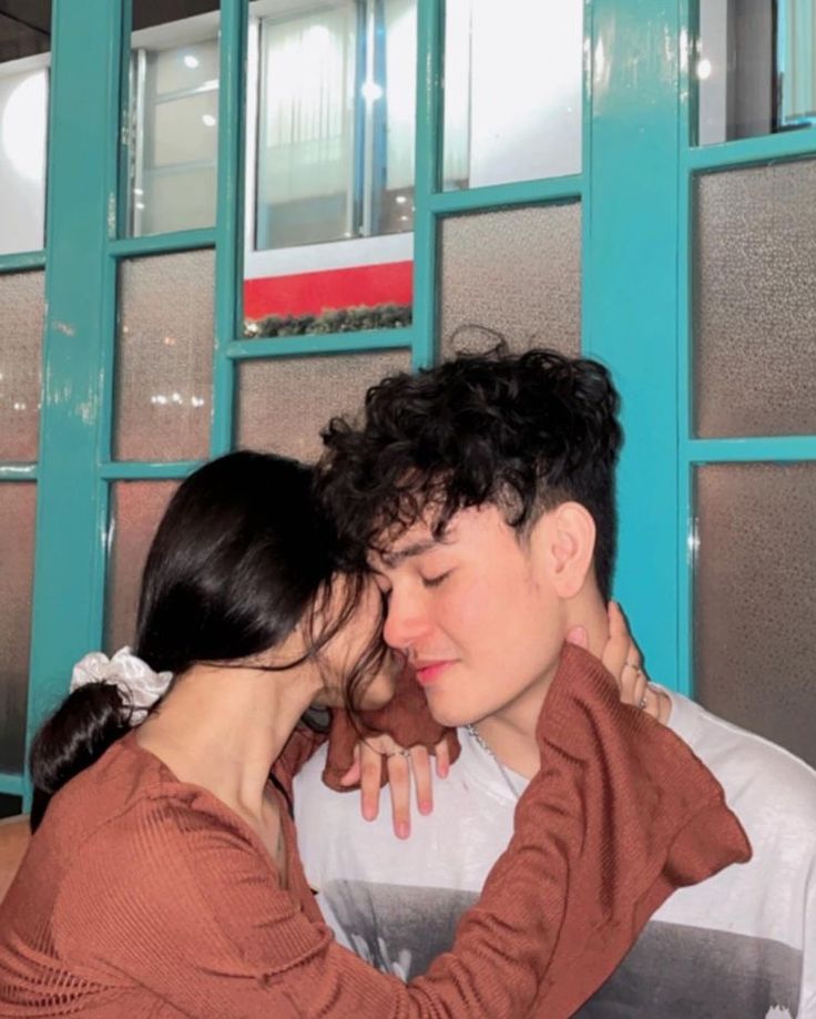 a man and woman embracing each other in front of blue doors