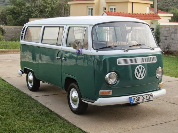 a green and white vw bus parked in front of a house