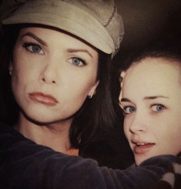 two beautiful young women standing next to each other in front of a mirror with one looking at the camera