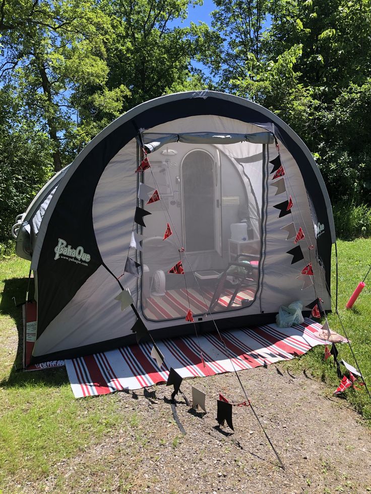 an outdoor tent is set up in the grass with its door open and it's awning opened