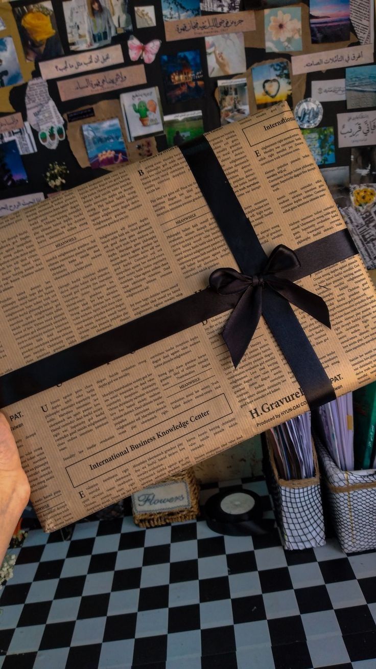 a large gift wrapped in brown paper with a black ribbon and bow sitting on top of a checkered table