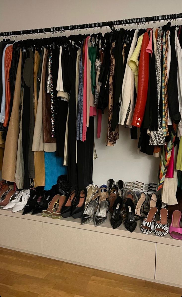 a closet filled with lots of different types of shoes and clothes hanging on the wall