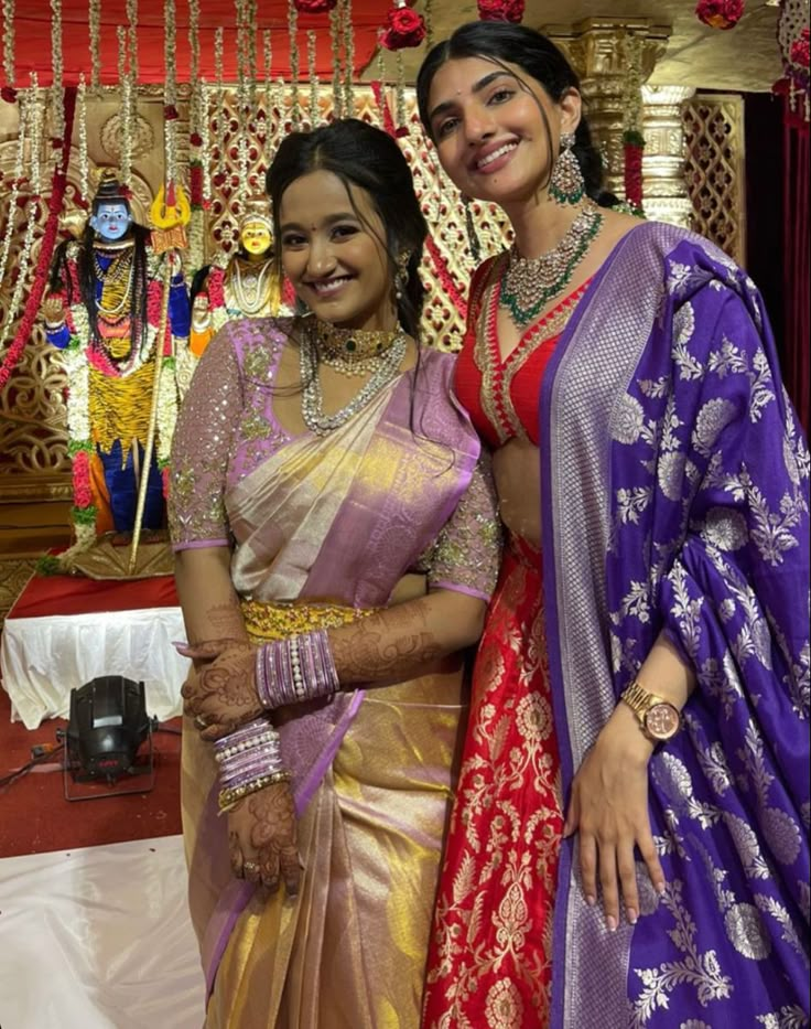 two women standing next to each other in sari