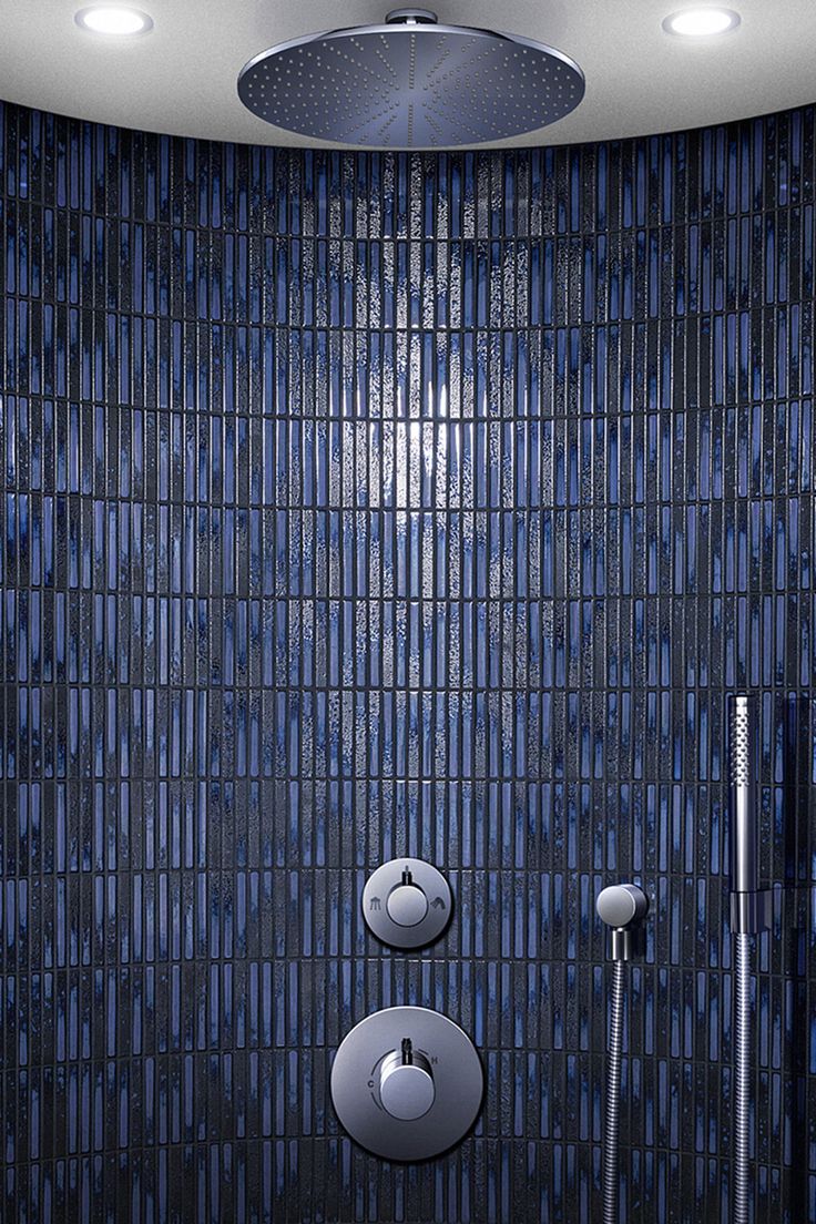 a blue tiled bathroom with two shower heads and three lights on the ceiling above it