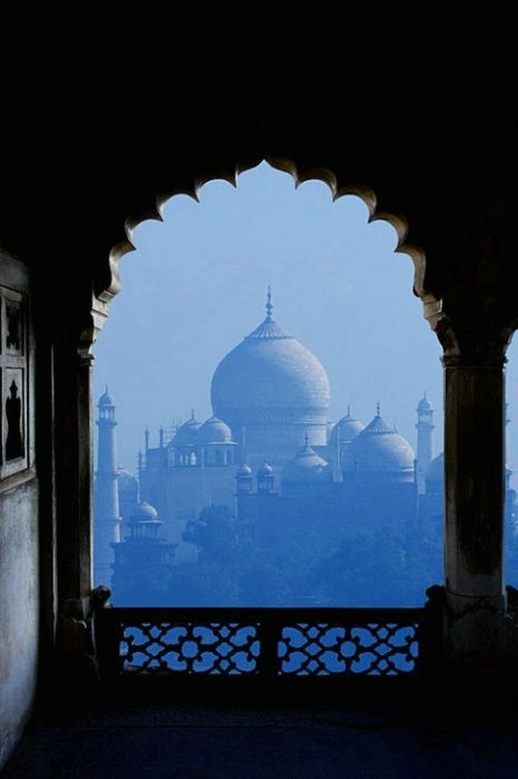 an archway with a view of the taj mulker in the distance from inside one of the buildings