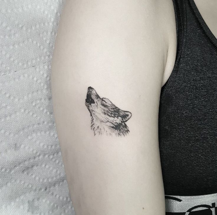 a woman's arm with a wolf tattoo on the left side of her arm