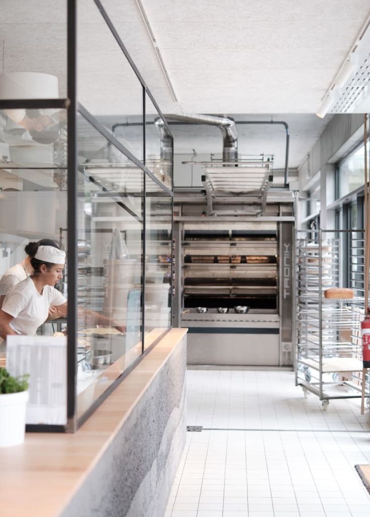 a woman standing in front of an oven inside of a kitchen next to a counter