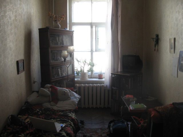 a room with a bed, bookcase and window in the corner next to a radiator