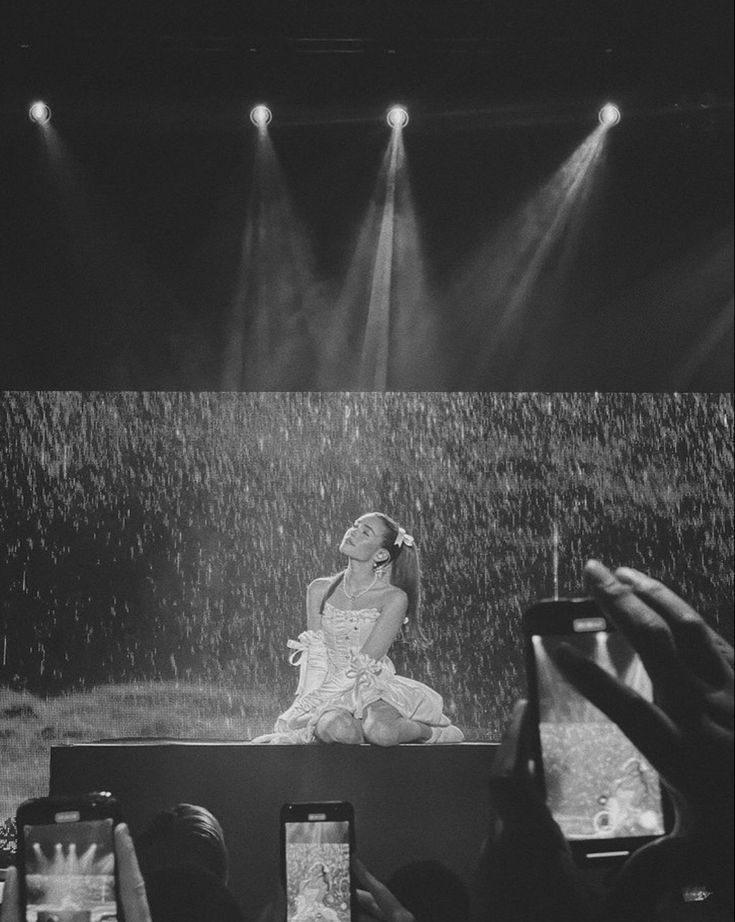 a black and white photo of a woman sitting in the rain