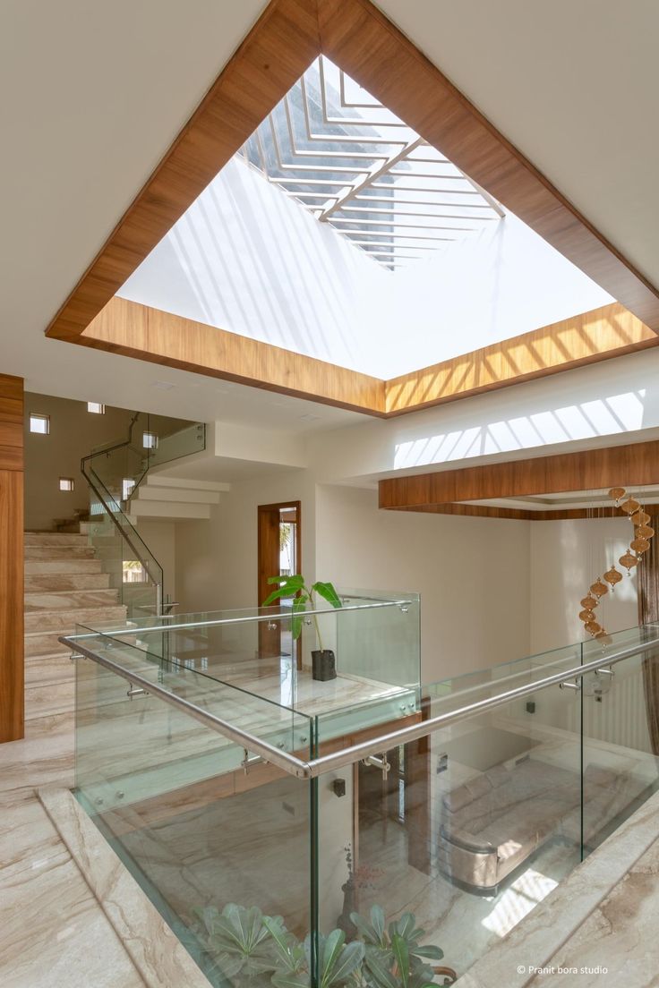 a glass railing in the middle of a room with stairs and skylight above it