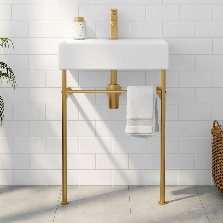 a white sink sitting under a bathroom mirror next to a towel rack and potted plant