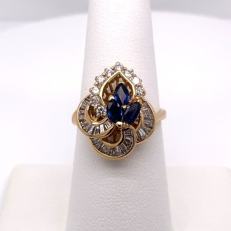 KARAT GOLD: 14K YELLOW GOLD  STYLE: SAPPHIRE & DIAMOND CONTAINS: (3) GENUINE MARQUISE SAPPHIRES (9) ROUND DIAMONDS (28) BAGUETTE DIAMONDS  GEMSTONE WEIGHT: .75CT GEMSTONE MEASUREMENTS: 4.8MM X 2.8MM DIAMOND WEIGHT: .83CT DIAMOND MEASUREMENTS: 2.0MM CLARITY: SI1 COLOR: H TOP OF RING MEASURES: 18.72MM FINGER SIZE: 7 GRAM WEIGHT: 5.4 ALL WEIGHTS ARE APPROXIMATE Gold And Sapphire Jewelry, Gold Marquise Diamond Sapphire Ring, Fine Jewelry Yellow Gold Sapphire Ring Pear-shaped, Fine Jewelry Yellow Gold Pear-shaped Sapphire Ring, Gold Sapphire Ring With Diamond In Pear Shape, Gold Pear-shaped Sapphire Ring With Diamond, Marquise Sapphire Ring With Diamonds In Gold, Gold Marquise Sapphire Ring In 14k Gold, Fine Jewelry Gold Marquise Sapphire Ring