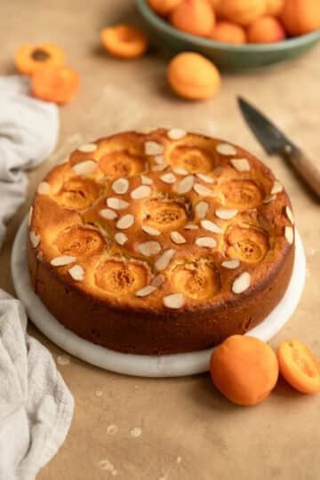 a cake sitting on top of a white plate next to oranges and a knife