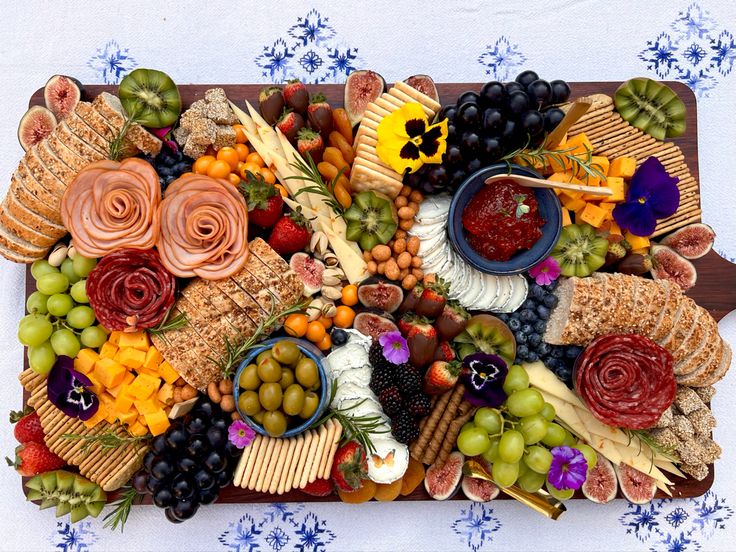 a platter filled with cheese, crackers, grapes, and other food items