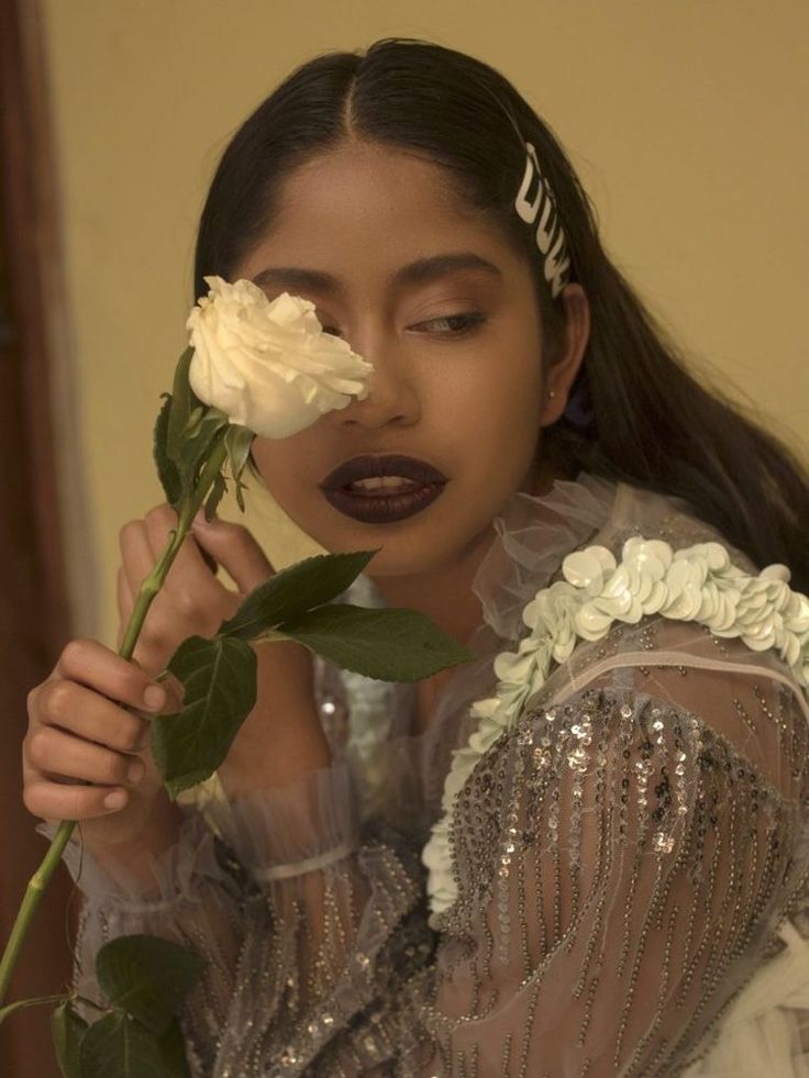 a woman holding a white rose in front of her face