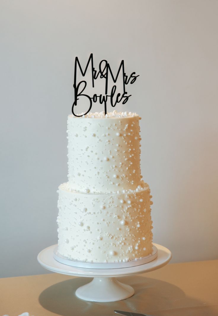 a three tiered cake with white frosting and black writing on top