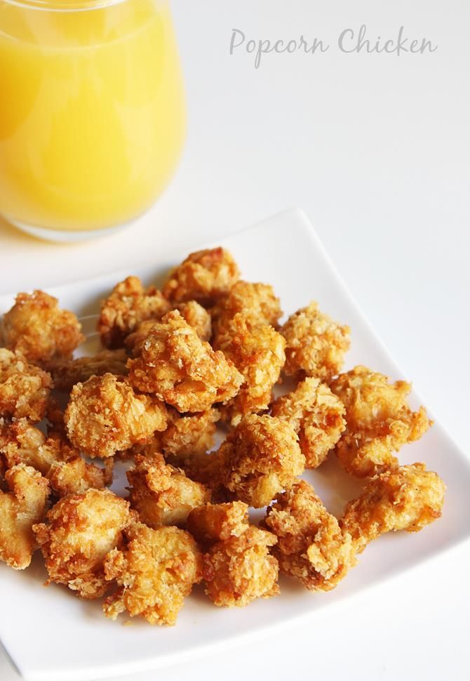 a white plate topped with fried tater tots next to a glass of orange juice