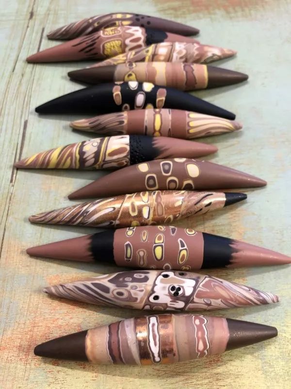 several different types of pens lined up in a row on top of a wooden table