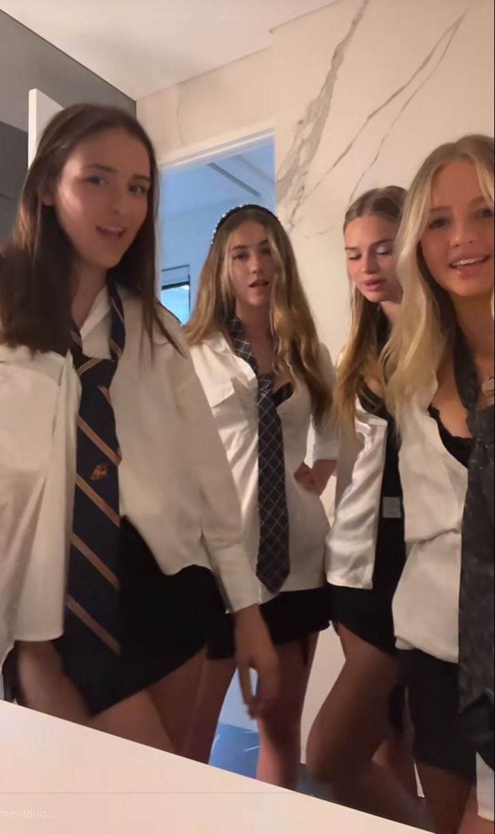 four young women dressed in school uniforms posing for the camera