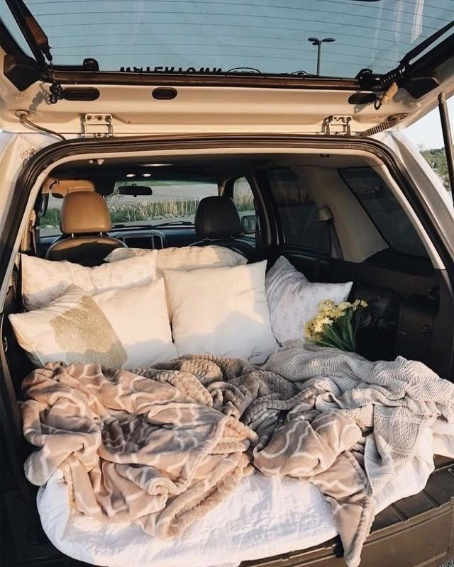 the back end of a car with pillows and blankets in it's trunk area