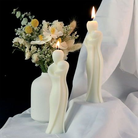 two white candles are next to a vase with flowers