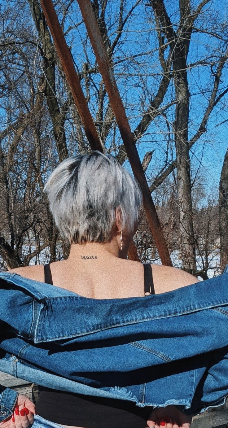 a woman sitting in a chair with her back turned to the camera, wearing blue jeans