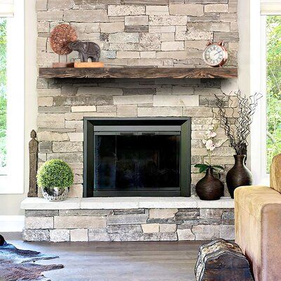 a living room with a stone fireplace and two vases on top of the mantel