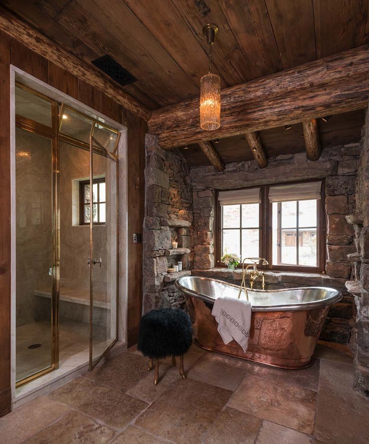 an old fashioned bathtub in a rustic bathroom with stone walls and flooring, along with a large window