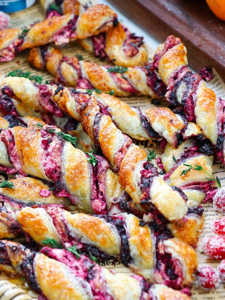 croissants with blueberry sauce and herbs on a tray next to oranges