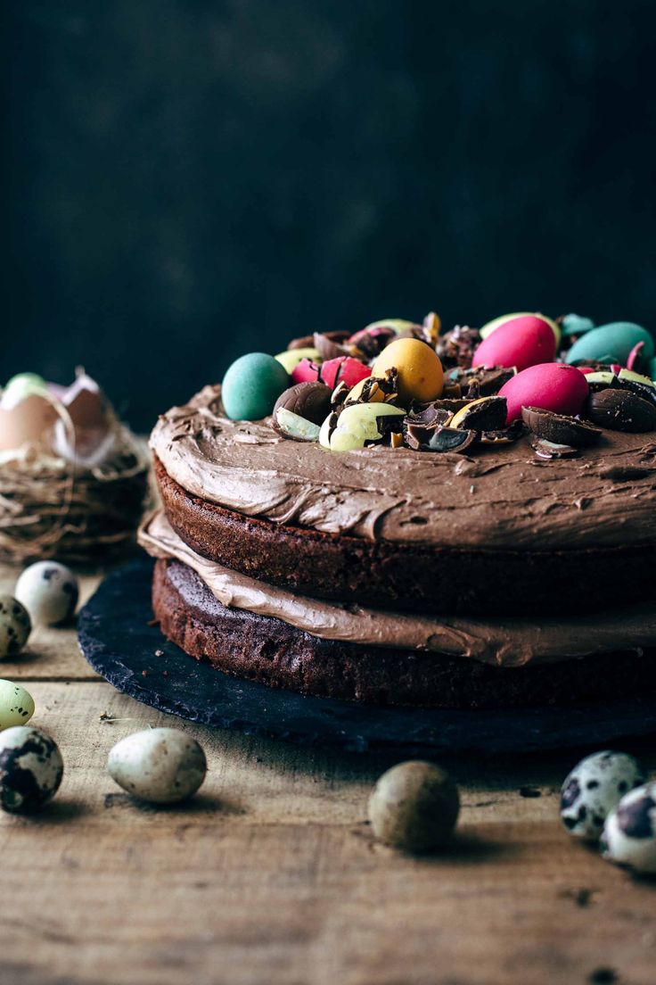 a cake with chocolate frosting and colored eggs around it