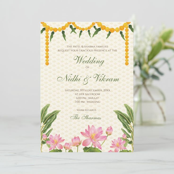 a wedding card with flowers and leaves on the front, sitting next to a vase