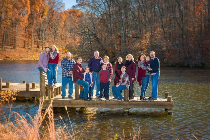 a group of people standing on a wooden dock next to a body of water with trees in the background