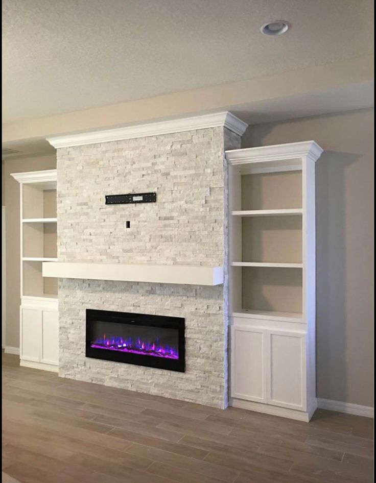 an empty living room with a fireplace and built - in bookcases