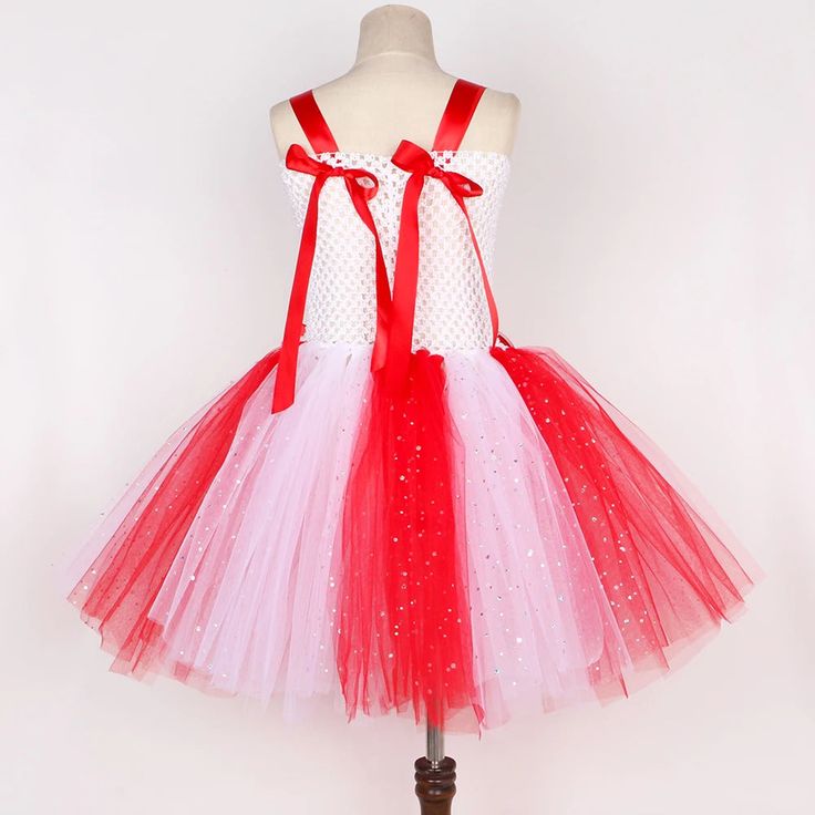 Extremely cue child tutu to be used for the Candy Canes in the ballet Nutcracker, or for any Christmas party. This pretty knee-length tutu features a white, stretchy top with silver glitter, and central red and white, striped insert. Satin red shoulder straps with candy canes pattern buttons. Redsatin bows also decorate the back of the costume. The tutu skirt is made with white and red glittery tulle, and is decorated by two red and white satin bows in the waist area. The costume also comes complete with a pretty red headband with striped red and white candy motif and glittery red bow, and with striped crochet socks. Available in sizes 1 to 12 years old. Fits small, so it is advisable to choose one size bigger. $ 65 White Tulle Christmas Dress, Pink Tulle Tutu Dress For Christmas, Christmas Princess Tutu Dress For Party, Christmas Party Princess Tutu Dress, Princess Tutu Christmas Party Dress, Carnival Tulle Tutu Dress, White Ballet Style Party Dress, Christmas Party Tutu Dress In Tulle, Holiday Party Tutu Dress Made Of Tulle