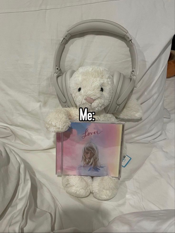 a white teddy bear sitting on top of a bed holding a book with the caption me