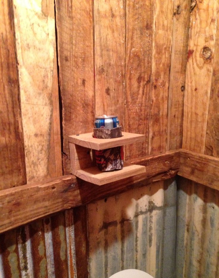 a toilet in a small room with wooden paneling on the walls and a shelf above it