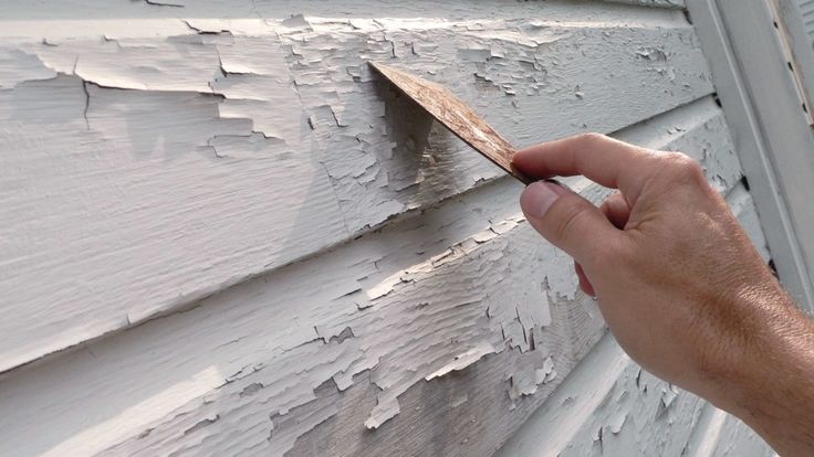 a person is painting the side of a house with white paint and brown wood shading