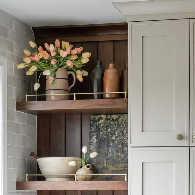 the shelves in the kitchen are filled with vases and bowls, including tulips