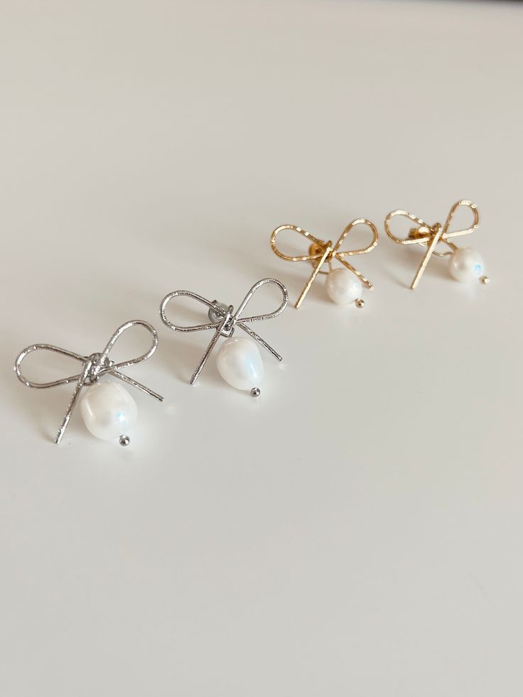 Look beautiful on any bridal occasion with the Bow Earring, a petite and minimalist accessory for a dainty touch of flair. Featuring a post back, bow detailing, and an authentic freshwater pearl, this flirty accessory is perfect for any special day. Details: Authentic fresh water pearls Material: Stainless Steel, 18k gold plated Final Sale Shipping: We offer flat rate shipping fees & free standard shipping on orders of $75 or more! Please allow up to 4 days for your order to process before shipp Dainty Pearl Charm Earrings For Parties, White Pearl Earrings With Bow For Wedding, Feminine Bow Jewelry For Wedding, Elegant Bow Jewelry For Weddings, Minimalist Party Jewelry With Bow, Elegant Wedding Jewelry With Bow, White Bow Earrings For Anniversary, White Bow Earrings For Wedding, Chic Bow Earrings For Wedding