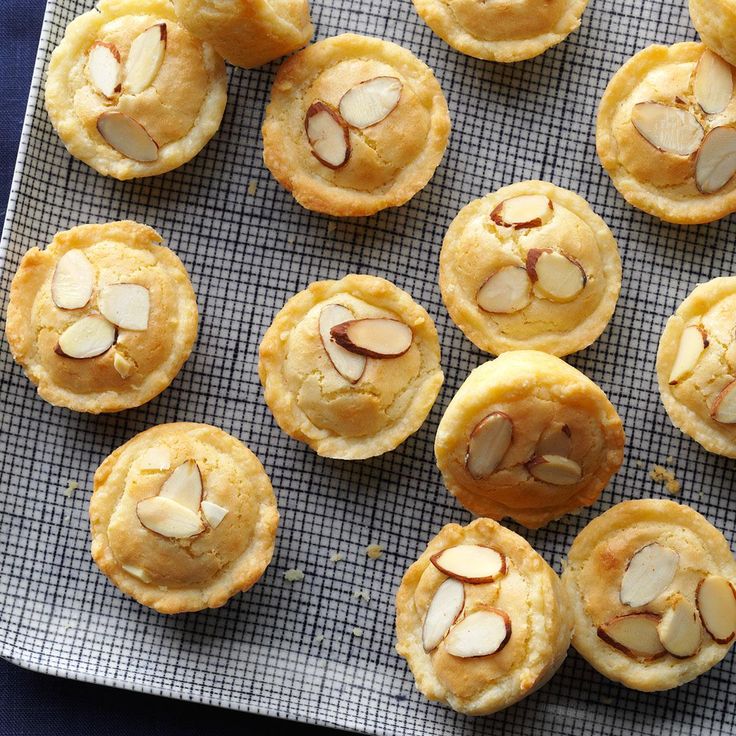 several cookies with almonds are on a baking sheet, ready to be baked in the oven