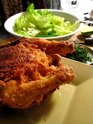 fried chicken and lettuce on a white plate next to a bowl of salad