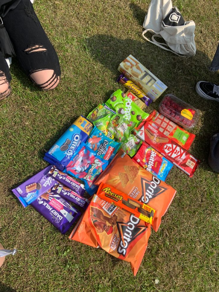 a group of people sitting on top of a grass covered field next to bags of candy