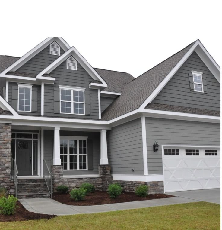 a gray house with white trim on the front and side windows, two car garages