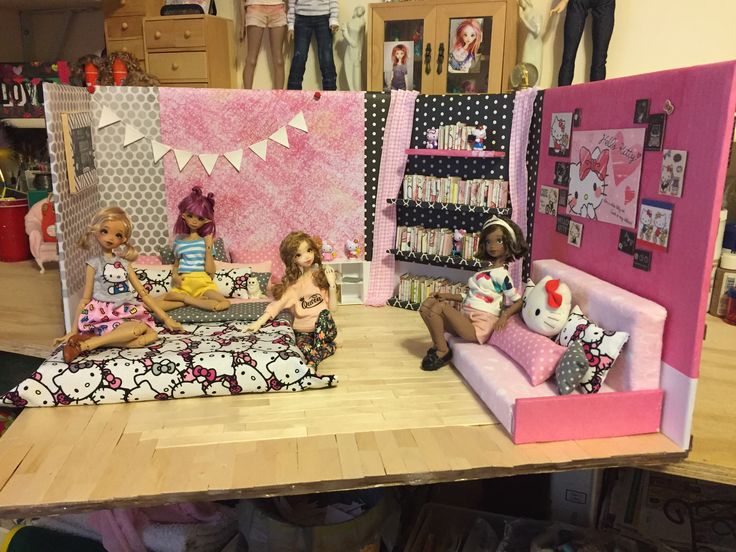 three dolls are sitting on a couch in front of a hello kitty doll house with pink walls and polka dot curtains