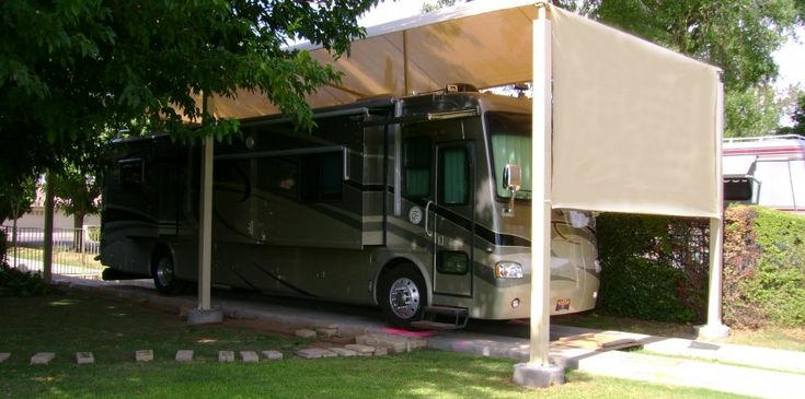 an rv parked under a canopy in the shade