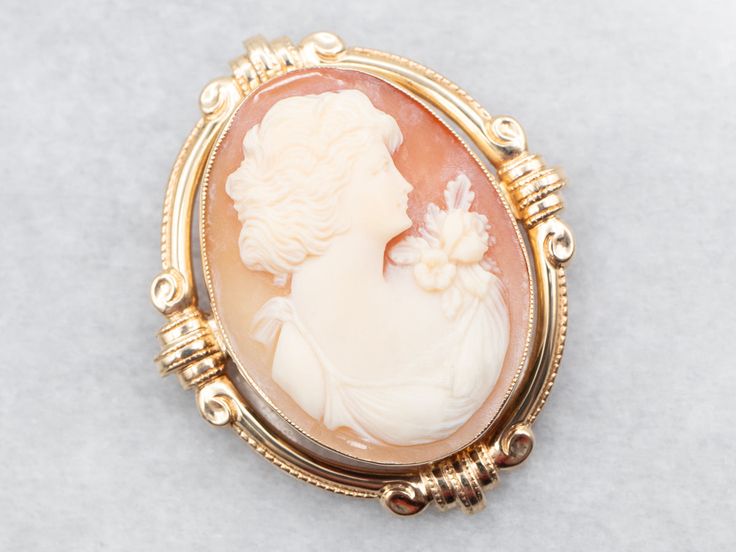 This beautiful vintage cameo brooch pendant features a lovely and proper lady with floral details. She has been set in a simple bezel with a Victorian-style frame, which completes the look of this sweet piece beautifully.This pendant does not come with the chain shown. Please feel free to contact us, we will help you find the perfect chain for your style and budget!Metal: 14K Yellow GoldGem: Shell CameoGem Measurements: 23.1 x 30.1 mm, OvalMeasurements: 32 x 39 mmMarks: "14K" Stamped on the pin clasp Classic Cameo Brooches For Wedding, Heirloom Cameo Brooch For Wedding, Heirloom Cameo Brooches For Weddings, Heirloom Cameo Wedding Brooch, Victorian Style Cameo Brooch For Weddings, Victorian Cameo Brooch For Wedding, Heirloom Cameo Brooch For Formal Occasions, Heirloom Style Cameo Brooch For Formal Occasions, Heirloom Cameo Brooches For Formal Occasions