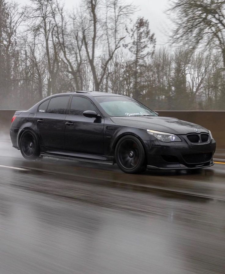 a black car driving down a wet road