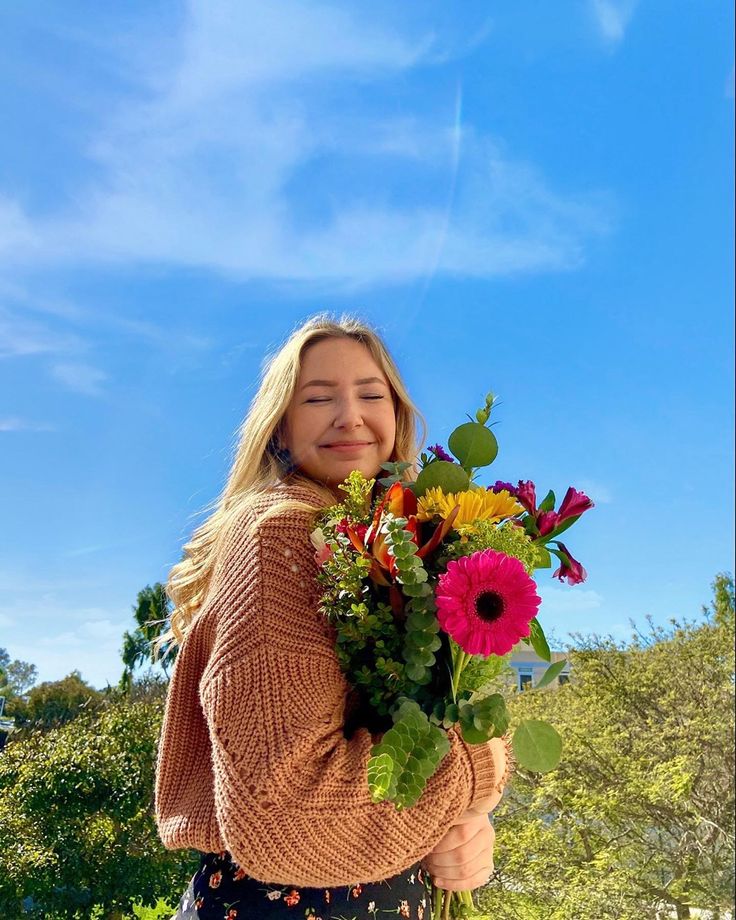 a woman holding a bouquet of flowers in her hands