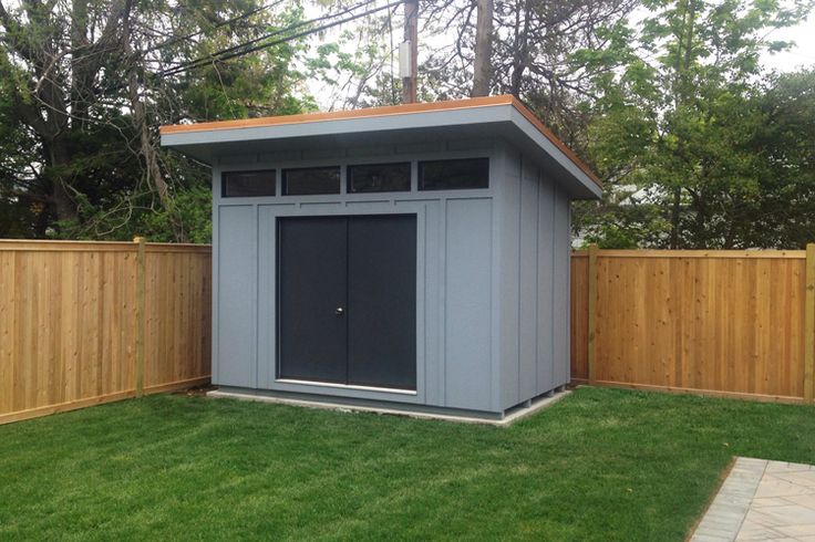 a small gray shed sitting in the middle of a yard