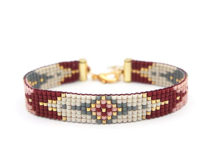 a red and white beaded bracelet with gold clasps on a white background,